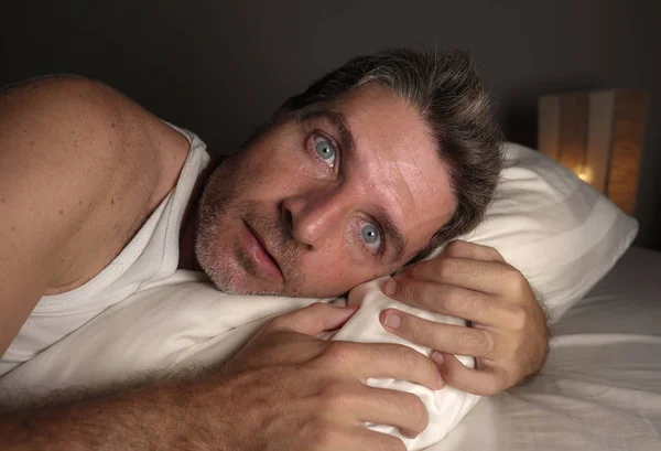 Portrait rapproché du visage d'un homme séduisant insomniaque et éveillé, les yeux grands ouverts la nuit, allongé sur son lit souffrant d'insomnie, essayant de dormir — Photo