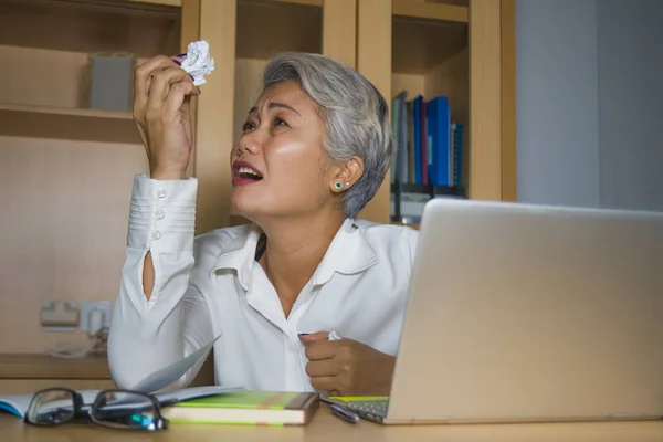 Çekici umutsuz ve stresli orta yaşlı Asyalı kadın sömürülen duygu ofis bilgisayar masasında çalışan ezilmiş ve aşırı çalışma gesturing çığlık — Stok fotoğraf