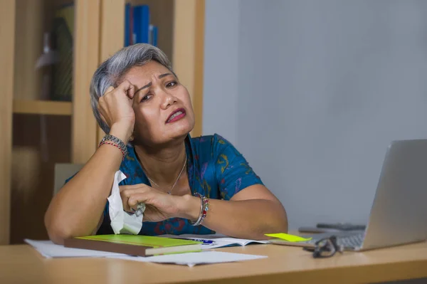 Depressive und überarbeitete attraktive asiatische Frau mittleren Alters, die im Stress am Laptop-Computer-Schreibtisch arbeitet, sich aufgeregt und überwältigt in aufgeregtem Gesichtsausdruck fühlt — Stockfoto