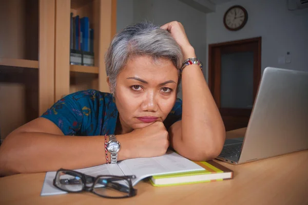 Déprimée et surmenée femme asiatique séduisante d'âge moyen travaillant dans le stress sur ordinateur portable bureau se sentant bouleversé et submergé dans l'expression du visage bouleversé — Photo