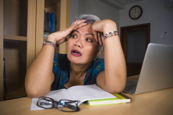 Depressive und überarbeitete attraktive asiatische Frau mittleren Alters, die im Stress am Laptop-Computer-Schreibtisch arbeitet, sich aufgeregt und überwältigt fühlt und unglücklich aussieht — Stockfoto