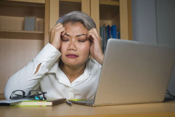 Déprimé et surchargé d'âge moyen attrayant asiatique femme travaillant dans le stress sur ordinateur portable bureau se sentant bouleversé et accablé regardant malheureux — Photo