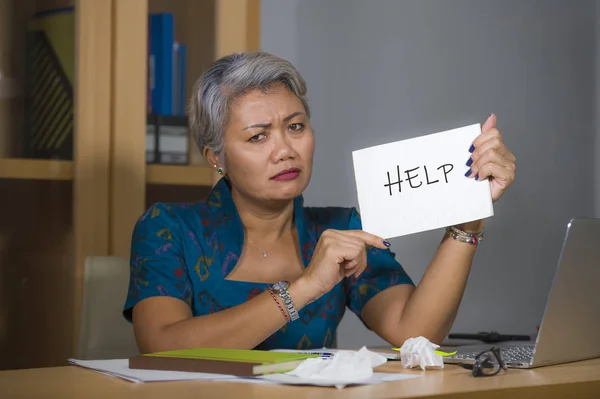 Zdesperowany i podkreślił atrakcyjne w średnim wieku Asian kobieta trzyma Notatnik prosząc o pomoc uczucie przepracowane i wykorzystywane pracy w biurze komputerowym biurko cierpienie stres — Zdjęcie stockowe