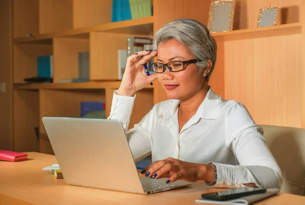 Lifestyle office portrait of attractive and happy successful middle aged Asian woman working at laptop computer desk smiling confident in entrepreneur business success — Stock Photo, Image