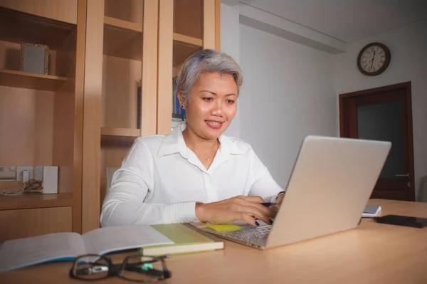 Natural lifestyle office portrait of attractive and happy successful mature Asian woman working at laptop computer desk smiling confident in entrepreneur success — Stock Photo, Image