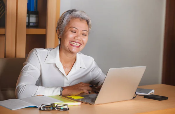 Stile di vita naturale ufficio ritratto di attraente e felice donna asiatica matura di successo che lavora alla scrivania del computer portatile sorridente fiducioso nel successo dell'imprenditore — Foto Stock