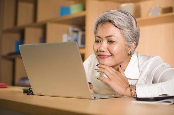 Természetes életmód irodai portréja vonzó és boldog sikeres érett ázsiai nő dolgozik a laptop számítógép asztal mosolygós magabiztos a vállalkozó siker — Stock Fotó