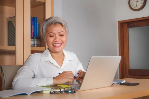 Lifestyle office portrait of attractive and happy successful middle aged Asian woman working at laptop computer desk smiling confident in entrepreneur business success — Stock Photo, Image