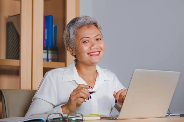 Lifestyle office portrait of attractive and happy successful middle aged Asian woman working at laptop computer desk smiling confident in entrepreneur business success — Stock Photo, Image