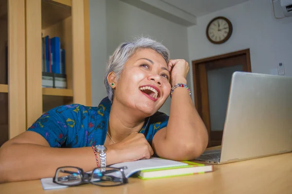 Estilo de vida escritório retrato de atraente e feliz bem sucedido de meia-idade mulher asiática trabalhando na mesa de computador portátil sorrindo confiante devaneio e sorrindo — Fotografia de Stock