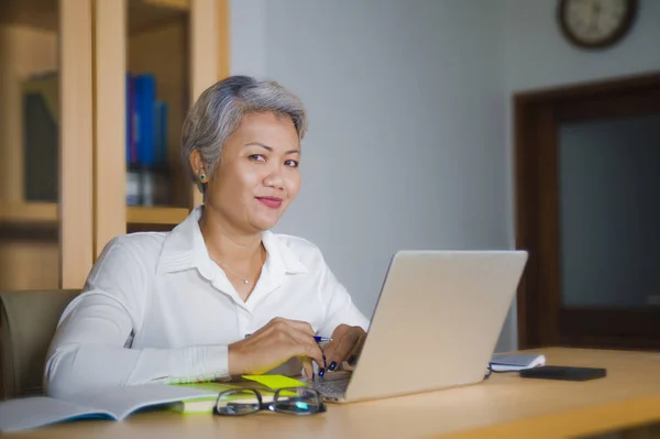 Corporate portret van aantrekkelijke en gelukkige succesvolle volwassen Aziatische vrouw werken bij laptop computer bureau glimlachend zelfverzekerd en charmant — Stockfoto