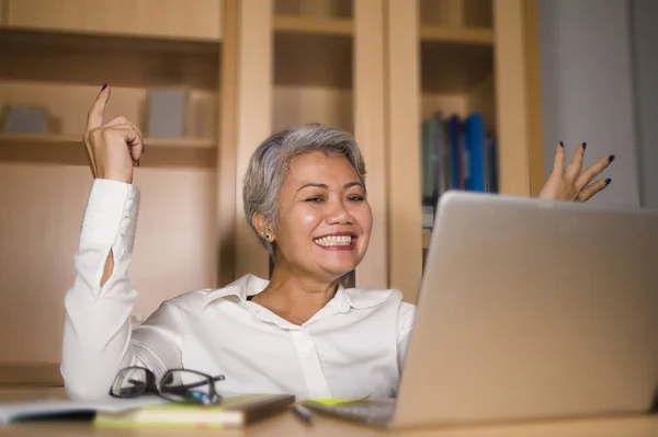 Ritratto aziendale di attraente e felice donna asiatica matura di successo che lavora alla scrivania del computer portatile sorridendo fiducioso e affascinante — Foto Stock