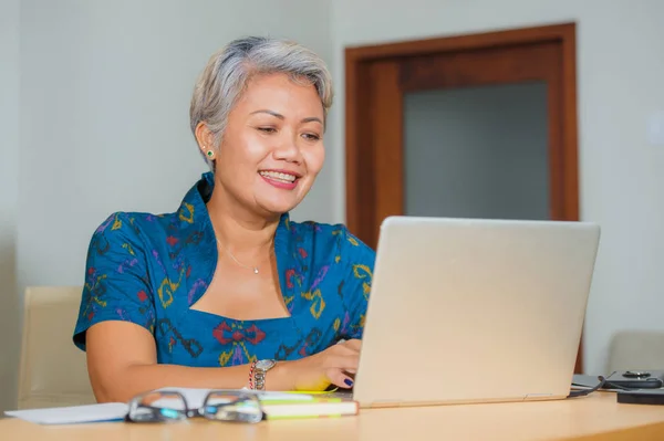 Stile di vita ritratto di felice e attraente elegante donna d'affari asiatica di mezza età che lavora sorridendo alla scrivania del computer dell'ufficio sentirsi positivo e di successo — Foto Stock