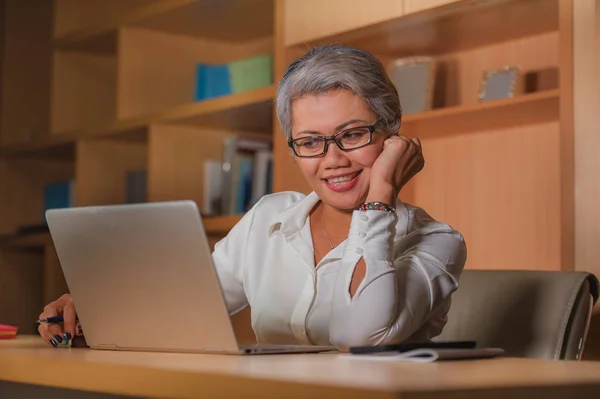 Lavoro aziendale stile di vita ritratto di felice e di successo attraente donna asiatica di mezza età che lavora alla scrivania del computer portatile ufficio soddisfatto ed efficiente nel successo aziendale — Foto Stock