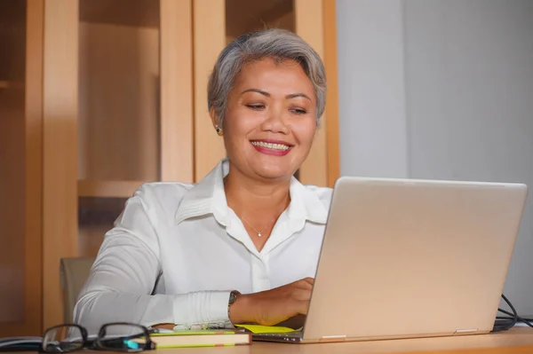 Lavoro aziendale stile di vita ritratto di felice e di successo attraente donna asiatica di mezza età che lavora alla scrivania del computer portatile ufficio soddisfatto ed efficiente nel successo aziendale — Foto Stock