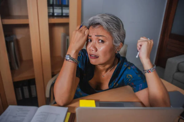 Привабливим підкреслив і перевантажений азіатських жінок, що працюють в офісі портативний комп'ютер стіл в стрес почуття розчарування і засмутився в бізнес-тиск і проблеми з роботою — стокове фото