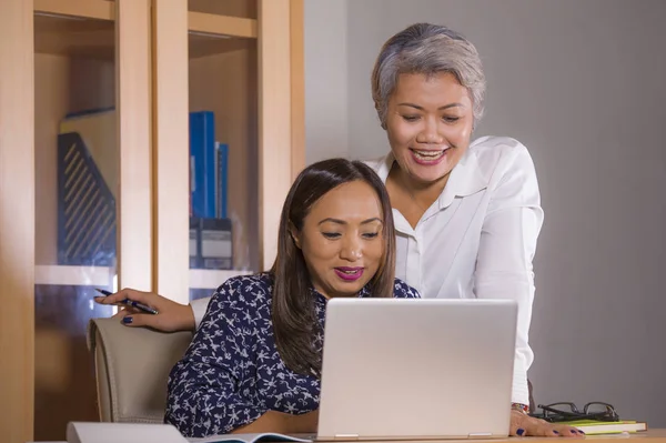 Natural lifestyle portrait of two business partners or work colleagues women collaborating and coworking happy and cheerful at office laptop computer desk — Stock Photo, Image