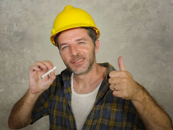Unternehmensportrait aus dem Baugewerbe: attraktiver und glücklicher Arbeiter mit Bauarbeiterhelm, der zuversichtlich lächelt und aufgibt, Zigarette zu rauchen, als erfolgreicher Unternehmer — Stockfoto