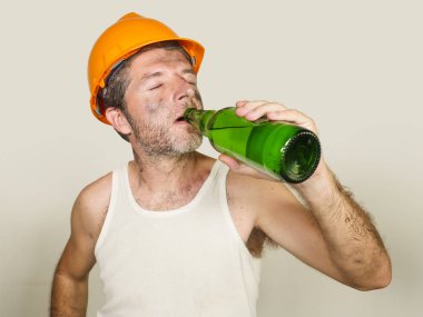 susuz ve yorgun yapıcı işçi veya inşaatçı adam güvenlik kaskı içinde stüdyoda izole iş molası sırasında ferahlatıcı soğuk bira şişesi içme yorgun hissediyorum