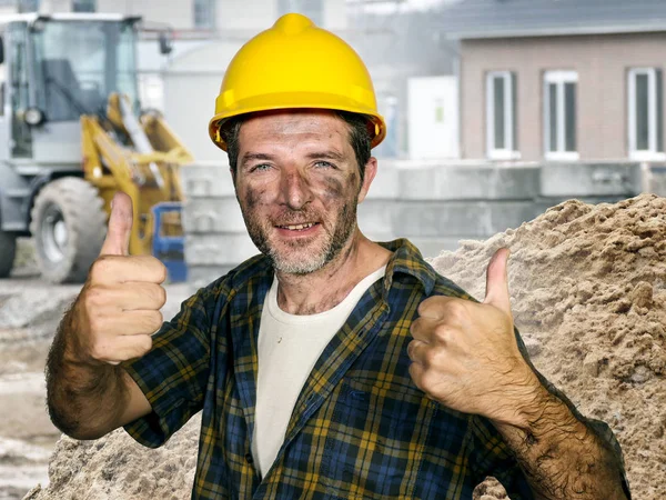 Jonge aantrekkelijke en zelfverzekerde aannemer of bouwvakker man met bouwvakker veiligheidshelm poseren corporate glimlachen vrolijk geven duim omhoog tevreden — Stockfoto