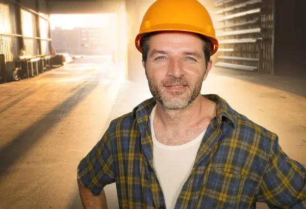 Attractive and happy workman in safety helmet smiling confident posing relaxed as successful contractor or handyman at warehouse site