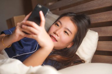 Kız arkadaşı ile cep telefonu sosyal medya manifatura kullanarak pijama genç güzel ve mutlu Asyalı Koreli kadın veya neşeli gülümseyen online dating app zevk