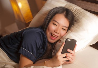 Kız arkadaşı ile cep telefonu sosyal medya manifatura kullanarak pijama genç güzel ve mutlu Asya Çinli kadın veya neşeli gülümseyen online dating app zevk