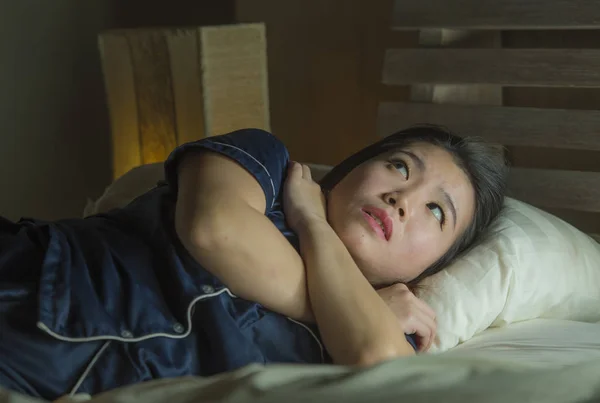 Joven sin dormir hermosa y asustada mujer coreana asiática acostada en la cama despierta por la noche sufriendo pesadilla después de ver la película de terror zombie con miedo y cara estresada — Foto de Stock