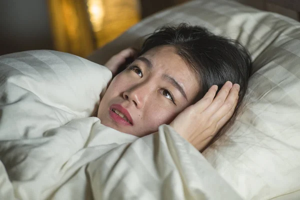 Genç uykusuz güzel ve korkmuş Asya Koreli kadın yatakta uyanık yatarken uyku korku zombi korku filmi izlerken ve yüz vurguladı sonra kabus acı — Stok fotoğraf