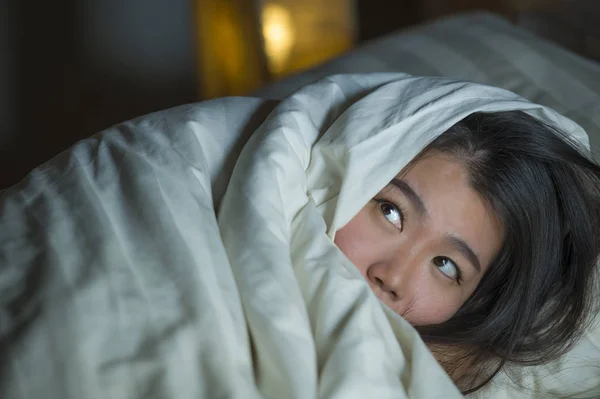 Young sleepless beautiful and scared Asian Chinese woman lying on bed awake at night suffering nightmare after watching zombie horror movie in fear and stressed face — Stock Photo, Image