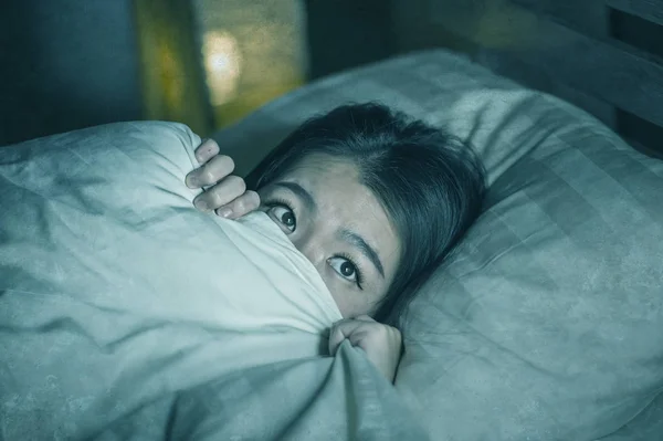 Jovem sem sono bonito e assustado asiático japonês mulher deitado na cama acordado à noite sofrendo pesadelo depois de assistir zumbi horror filme no medo e estressado rosto — Fotografia de Stock