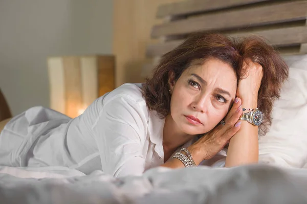 Dramatisches Lebensstil-Porträt einer attraktiven, traurigen und depressiven Frau mittleren Alters um die 50, die sich allein im Bett aufgeregt fühlt und unter Depressionen und Angstzuständen leidet — Stockfoto
