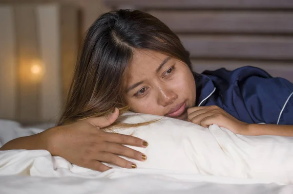 Drámai életmód portré fiatal vonzó szomorú és nyomott ázsiai nő pizsama fekve az ágyban a fájdalom szenvedés depresszió és a szorongás érzés magányos és kétségbeesett — Stock Fotó