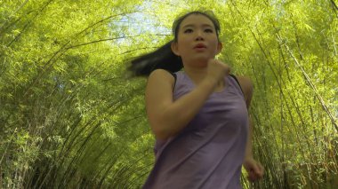 Genç, çekici ve aktif Asyalı, at kuyruklu Çinli kadın. Güzel şehir parkında egzersiz yapıyor. Sağlıklı yaşam tarzı ve spor eğitimi alıyor.