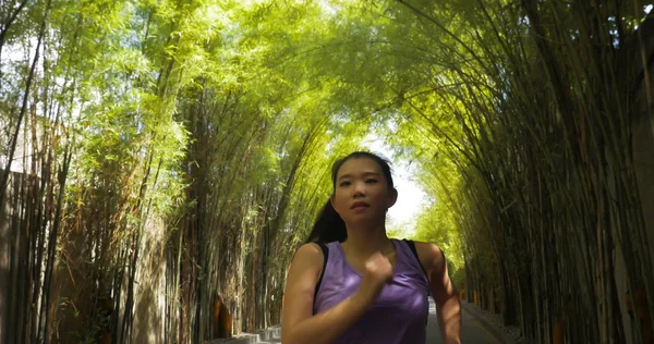 young attractive and active Asian Chinese woman with pony tail running practicing jogging workout at beautiful city park in healthy lifestyle and sport training