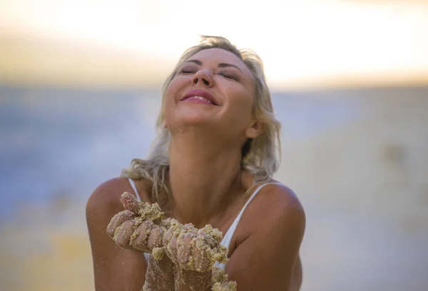 Schöne und sexy blonde Haare Frau im Bikini posiert glücklich und entspannt am tropischen Strand im Urlaub Kurzurlaub spielen mit nassem Sand in seinen Händen — Stockfoto