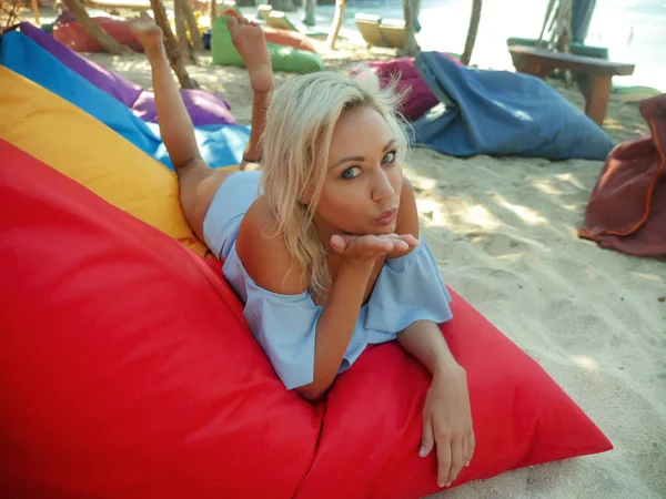 Jeune belle et heureuse femme blonde aux yeux bleus détendue et réfrigérée allongée sur un hamac de sac à haricots sous le soleil portant un bikini classique élégant profitant de vacances — Photo