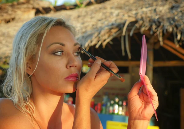 Blond dama i zrelaksowany cień kobiece kobieta lustro makijaż odwłoka piękny plaża przytrzymanie pędzel siedzący w wakacje — Zdjęcie stockowe