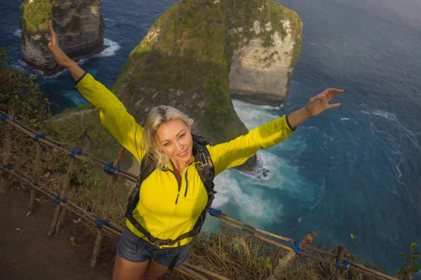 young beautiful and happy hiker woman with backpack hiking on sea mountain cliff exploring tropical destination enjoying solo travel trekking adventure holiday