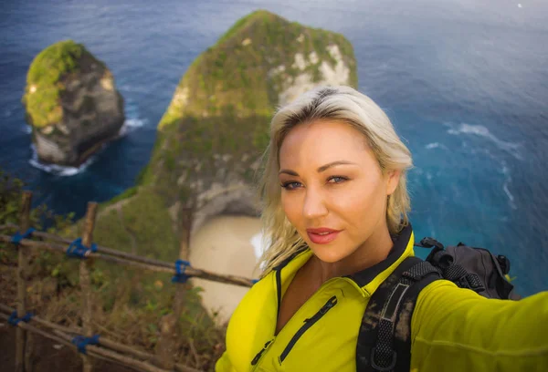 Joven hermosa y feliz mujer excursionista con mochila senderismo en el acantilado de montaña de mar tomar retrato selfie con teléfono móvil disfrutando de viajes en solitario aventura trekking — Foto de Stock