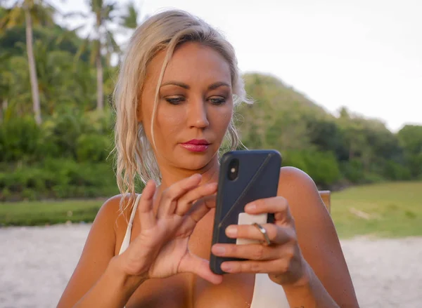 Lifestyle-Porträt einer jungen attraktiven und entspannten blonden Frau, die per Handy-Internet-App SMS schreibt oder Futter an tropische Naturstrände schickt — Stockfoto