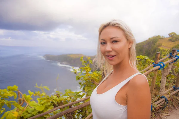 Mujer turista rubia feliz sintiéndose libre en la impresionante vista de la hermosa playa acantilado del mar en el mirador disfrutando de exóticas vacaciones de verano escapada en el paraíso tropical —  Fotos de Stock