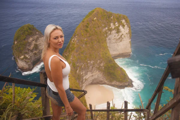 Glückliche blonde Touristin, die sich frei fühlt auf dem atemberaubenden Blick auf den wunderschönen Strand der Klippen am Aussichtspunkt und einen exotischen Sommerurlaub im tropischen Paradies genießt — Stockfoto