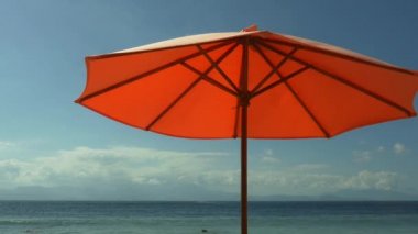 Turuncu plaj şemsiyesi ada kaçamak Yaz tatili ve seyahat hedef kavramı mavi deniz önünde tropikal cennet plajda rüzgar çarptı
