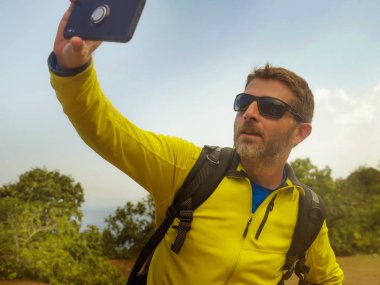 genç mutlu ve çekici sportif yürüyüşçü adam yürüyüş sırt çantası ile dağda yürüyüş selfie alarak doğa ve çevreyi keşfetmek seyahat kaçamak zevk