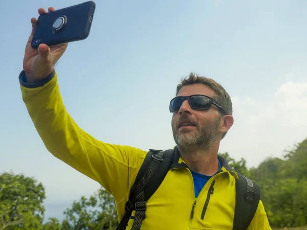 Ung lycklig och attraktiv sportig vandrare man med Trekking ryggsäck vandring på berget tar Selfie njuter resa flyktbilen utforska natur och miljö — Stockfoto