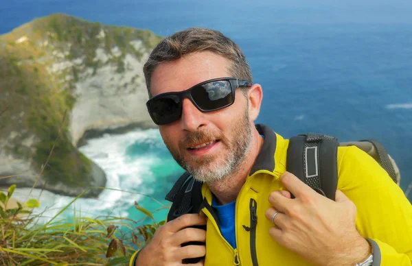 Jovem feliz e atraente caminhante desportivo homem com caminhadas mochila caminhadas no mar penhasco paisagem sentindo-se livre apreciando viagem fuga explorando a natureza e o meio ambiente — Fotografia de Stock