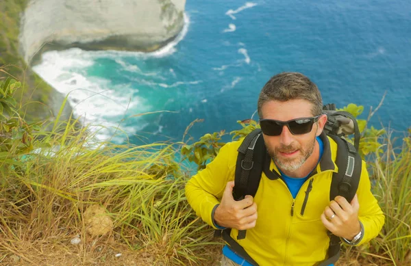 Unga glada och attraktiva sportiga vandrare man med Trekking ryggsäck vandring på Sea Cliff landskap Känn dig fri att njuta av resor flyktbilen utforska natur och miljö — Stockfoto