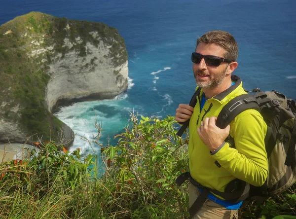 Joven hombre excursionista deportivo feliz y atractivo con mochila de trekking senderismo en el paisaje del acantilado del mar sentirse libre disfrutando de una escapada de viaje explorar la naturaleza y el medio ambiente — Foto de Stock