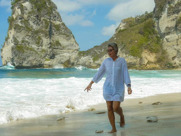 Vacaciones estilo de vida retrato de mujer madura asiática feliz y relajada en sus años 50 con el pelo gris caminando en el paraíso tropical playa del desierto bajo un cielo azul de verano disfrutando — Foto de Stock
